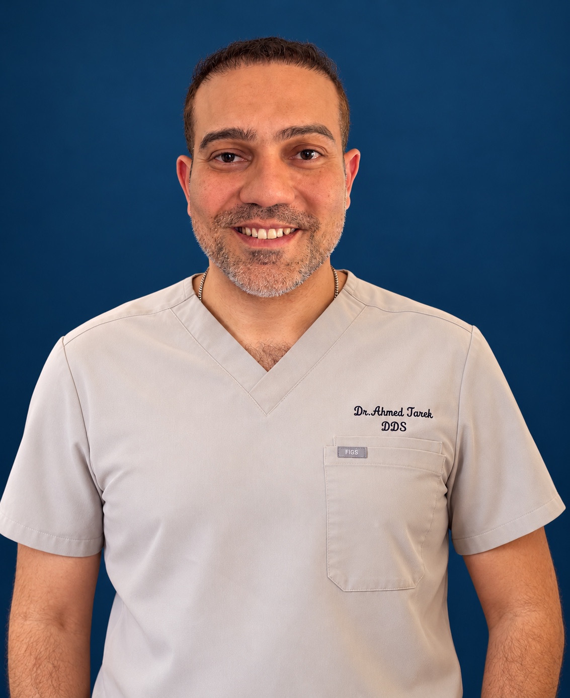 Dr. Ahmed Tarek smiling in his clinical scrubs